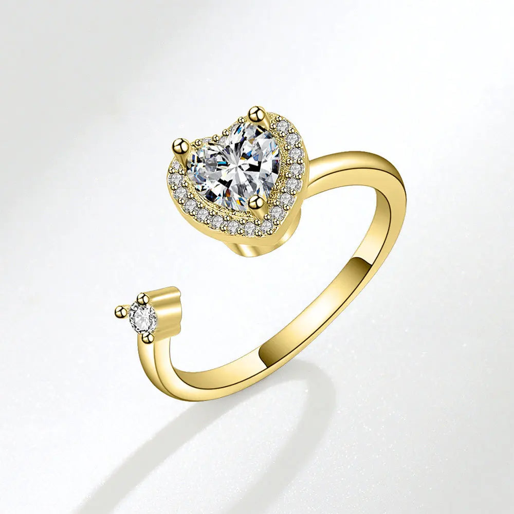 Gold ring with heart-shaped diamond on a light gray background