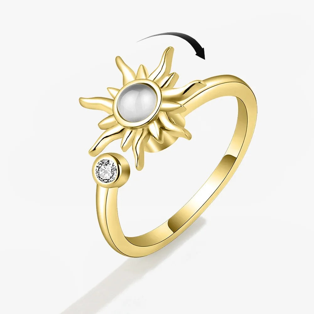 Gold ring with sun design and pearl center on a white background