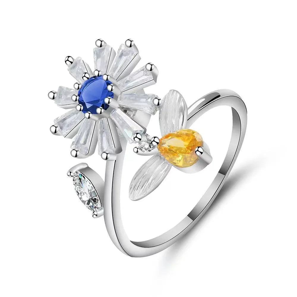 Silver ring with floral design and gemstones on a white background
